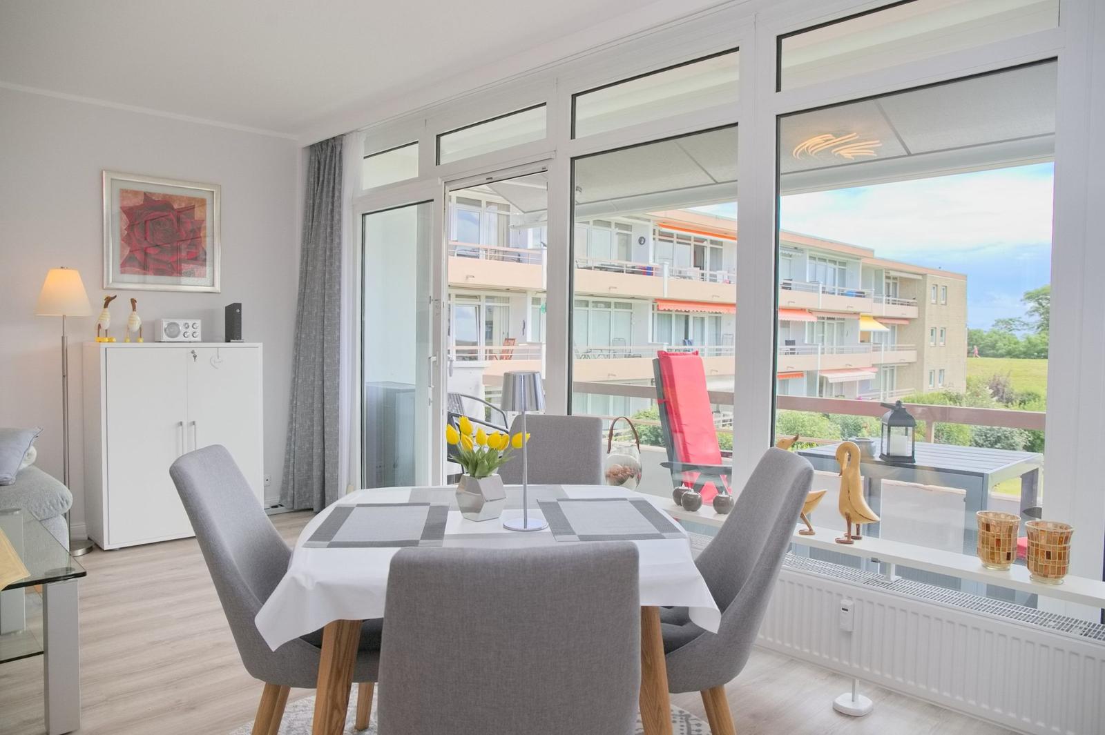 Esszimmer mit Tisch, Stühlen und Blick auf Balkon mit Sitzgelegenheiten.