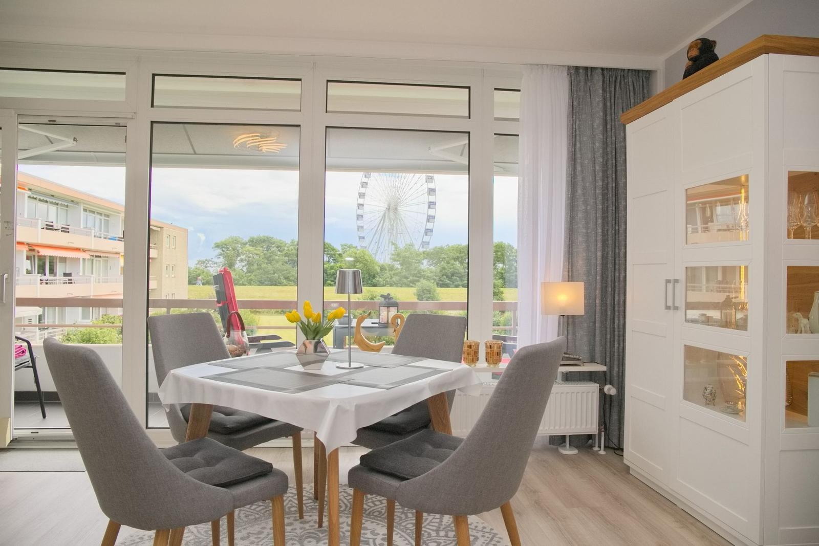 Essbereich mit Tisch und Stühlen. Durch Fenster Blick auf Riesenrad.