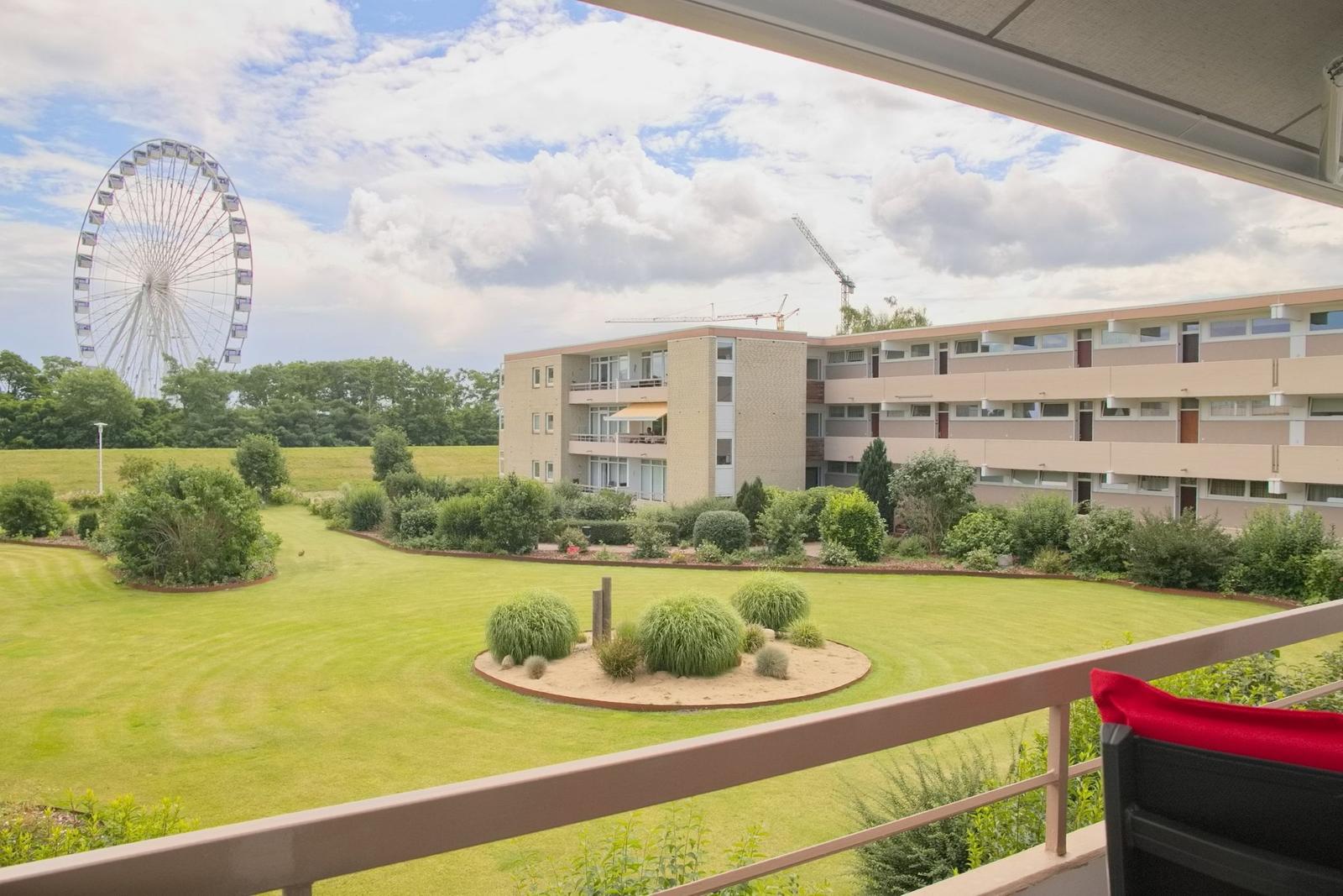 Balkon mit Blick auf Grünfläche, Gebäude und Riesenrad.