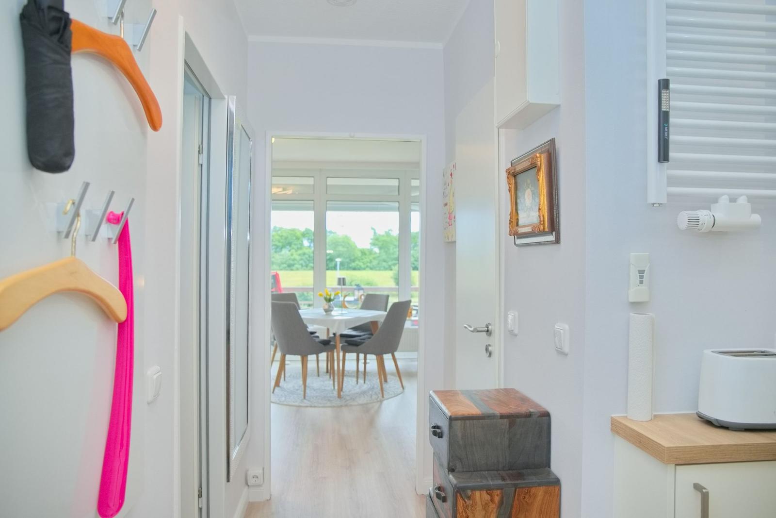 Flur mit Garderobe, Küchenzeile und Blick in Esszimmer mit Tisch und Stühlen.