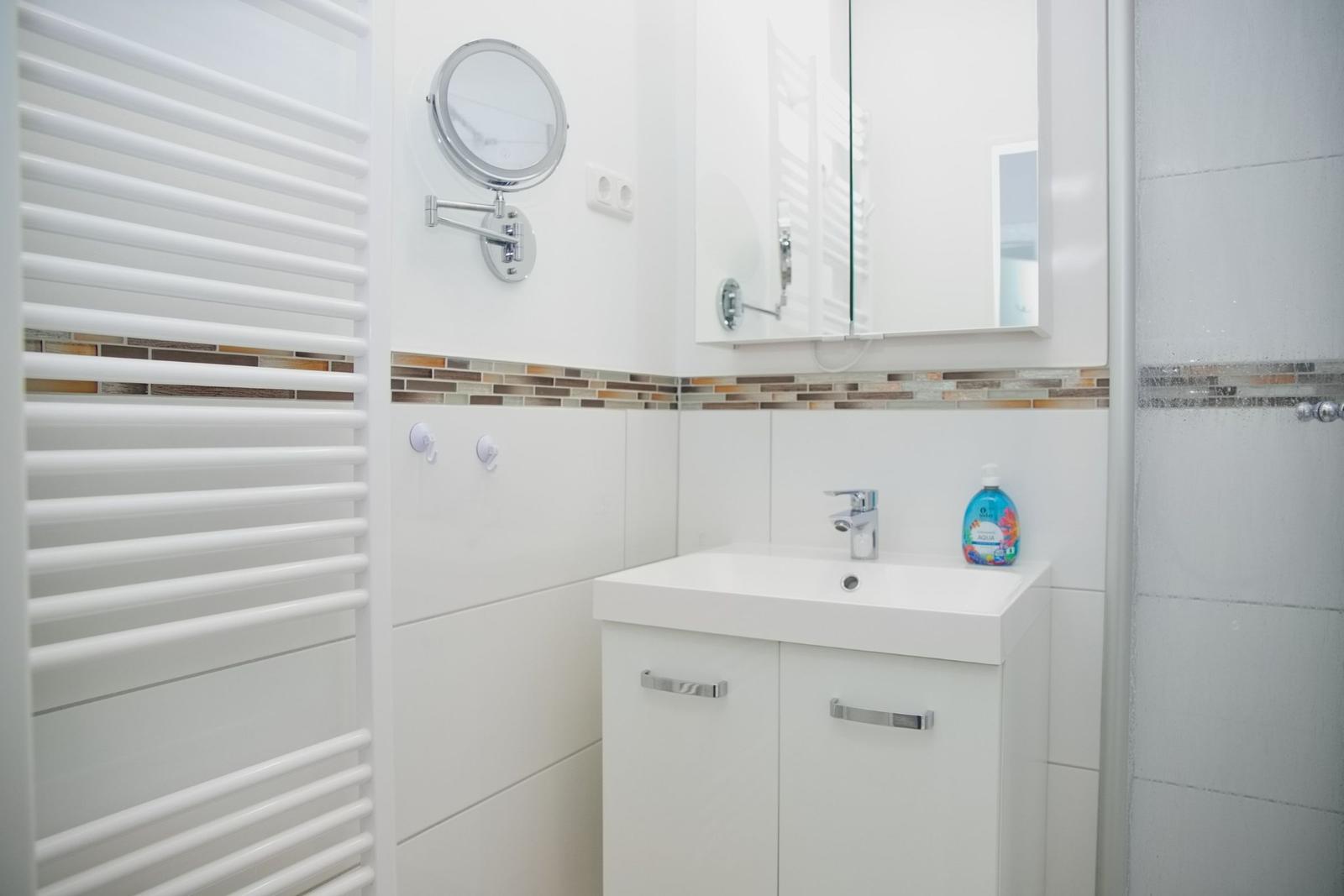 Badezimmer mit Waschbecken, Spiegel und Heizkörper.