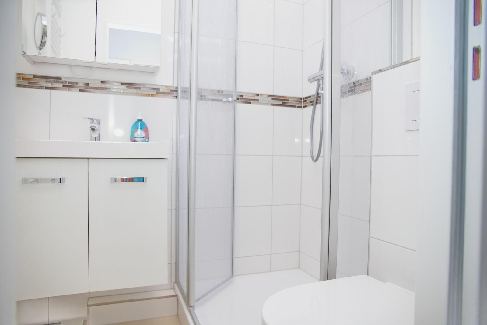 Badezimmer mit Dusche, Waschbecken und Toilette.