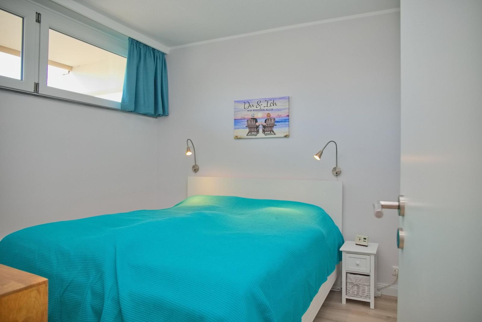 Schlafzimmer mit Bett, Nachttisch und Wandbild.