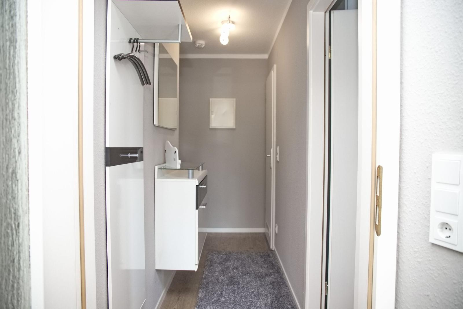 Flur mit Kleiderschrank, Spiegelschrank und Teppichboden.