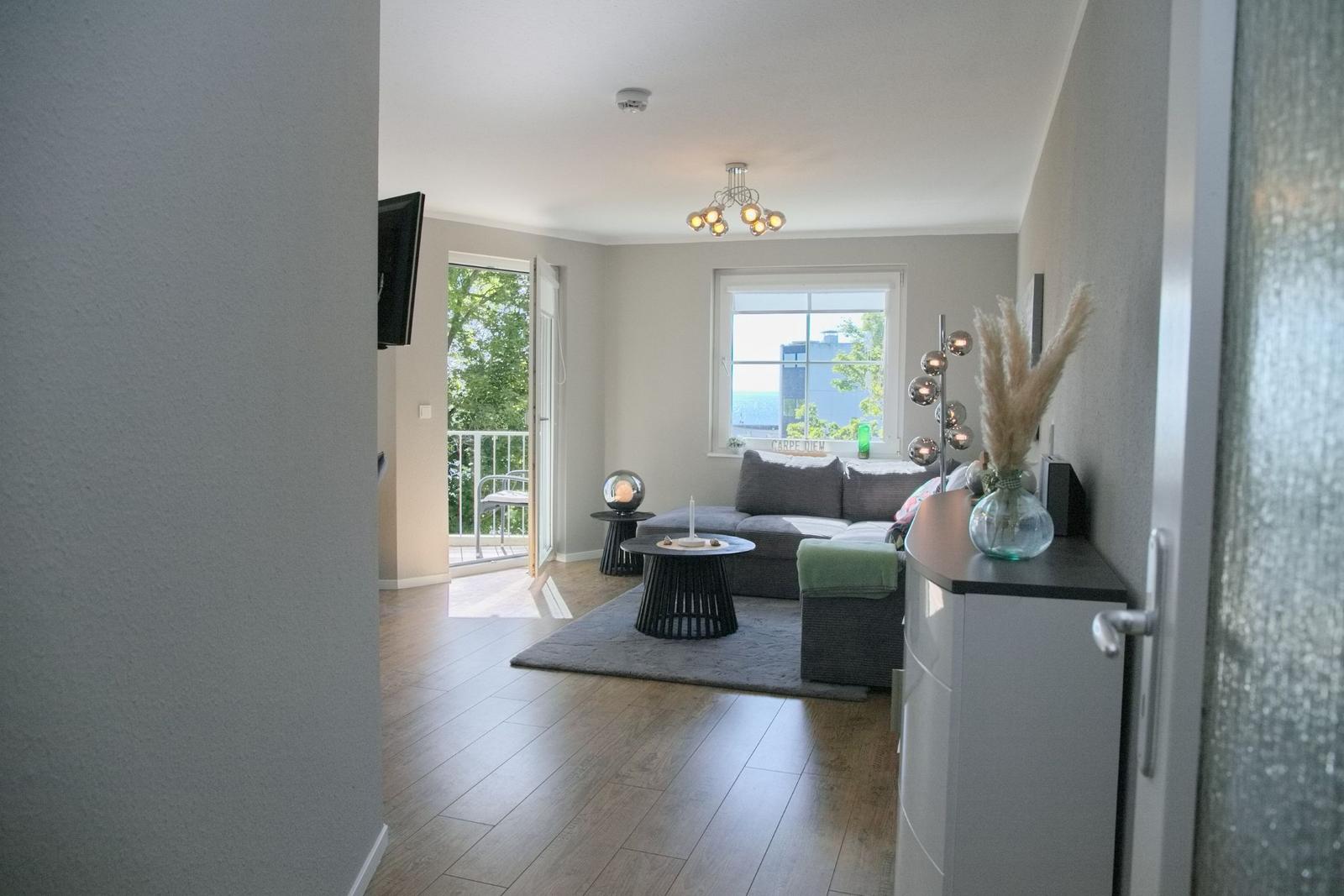 Wohnzimmer mit Sofa, Tisch und Fensterblick auf Meer