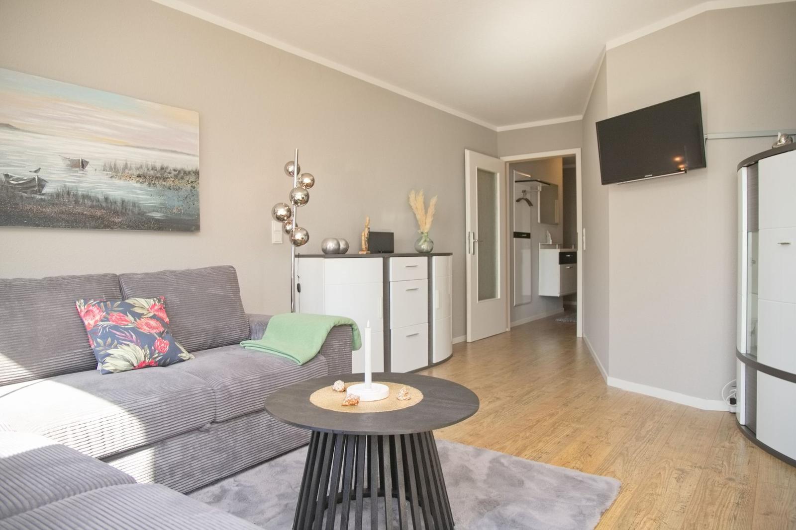 Wohnzimmer mit Sofa, Couchtisch und Fernseher an der Wand.