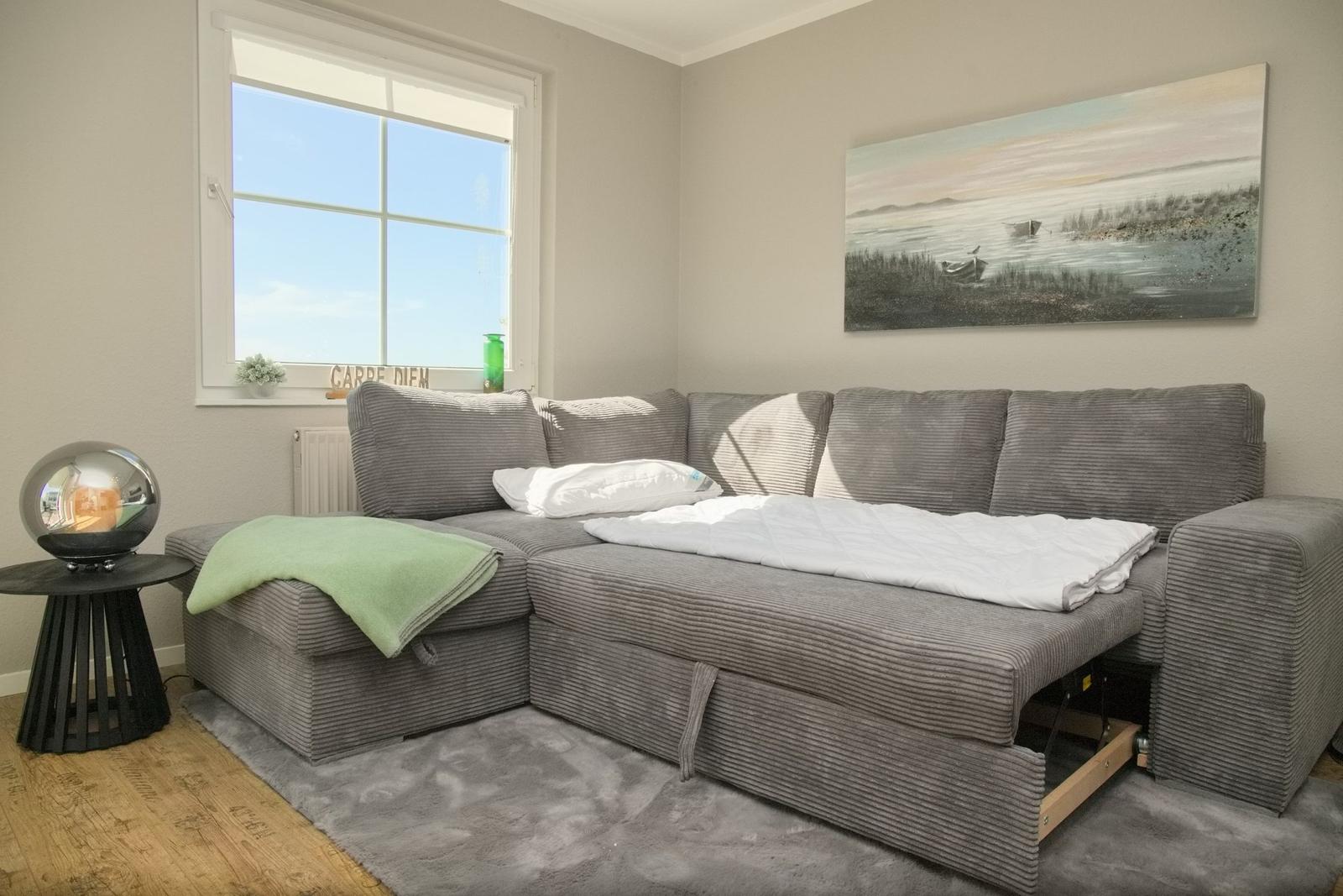 Großer grauer Schlafsofa mit Bett, Wandbild und Fenster mit Blick.