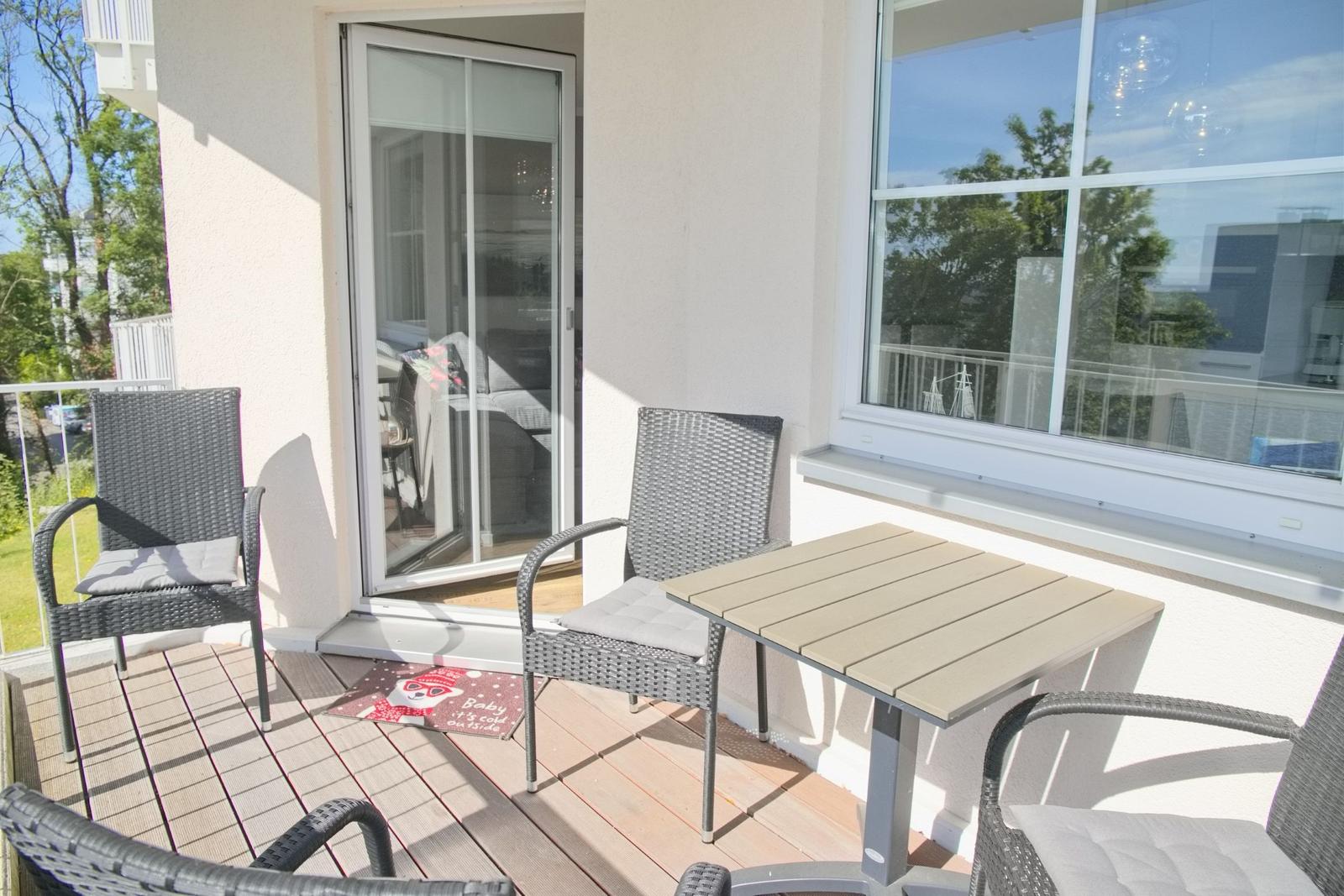 Terrasse mit Tisch und Stühlen, Schiebetür und Fenster zur Wohnung.