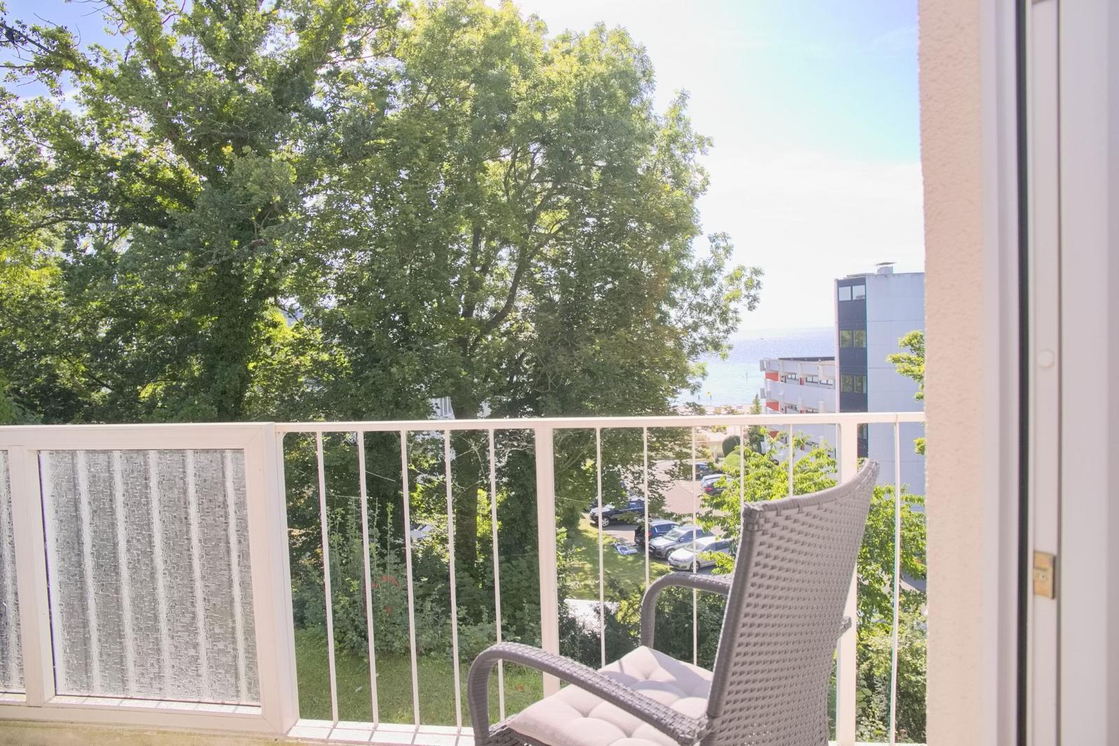 Balkon mit Stuhl und Blick auf Bäume und Meer