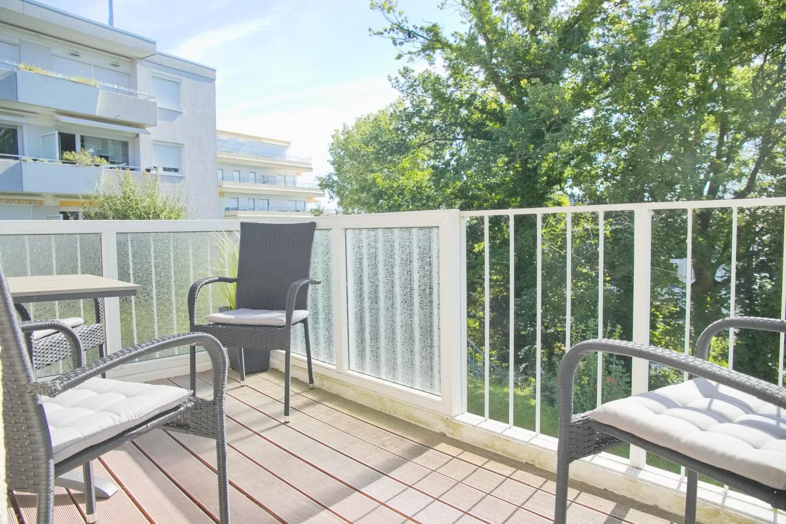 Terrasse mit Gartenmöbeln und Blick auf Bäume und Gebäude