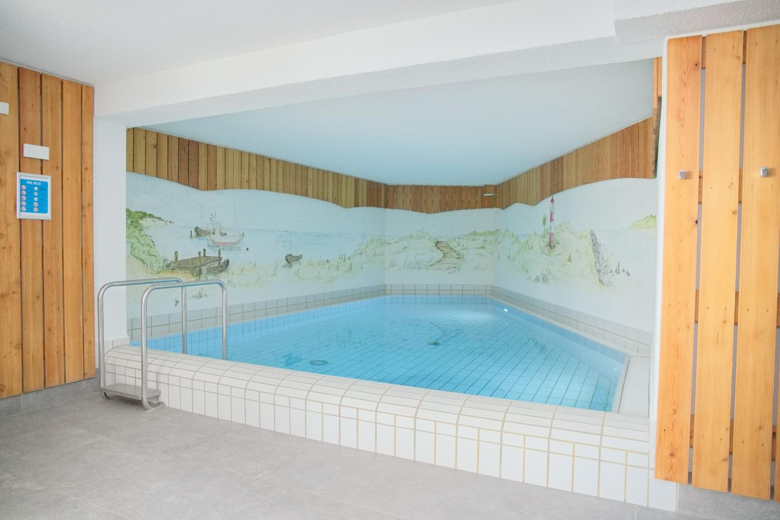 Innenpool mit Meeresmotiven an den Wänden und Holzwandverkleidung.
