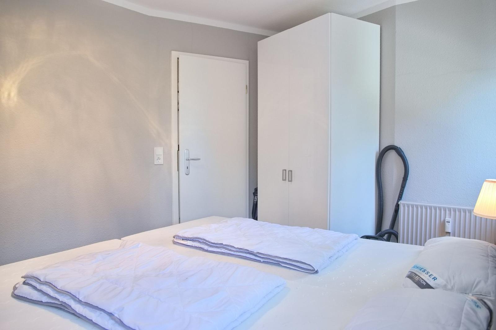 Schlafzimmer mit Bett, Kleiderschrank und Saugrohr.