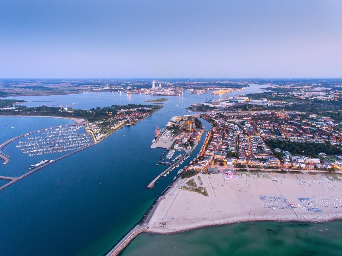 Aerial view of coastal town with harbor, beach, and marina at dusk.