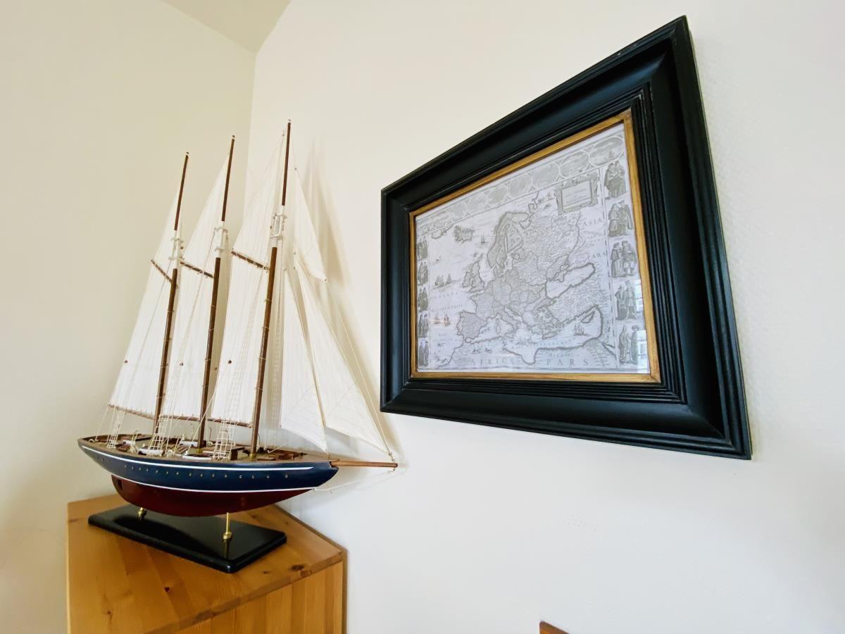 Segelschiffmodell und historische Weltkarte an der Wand