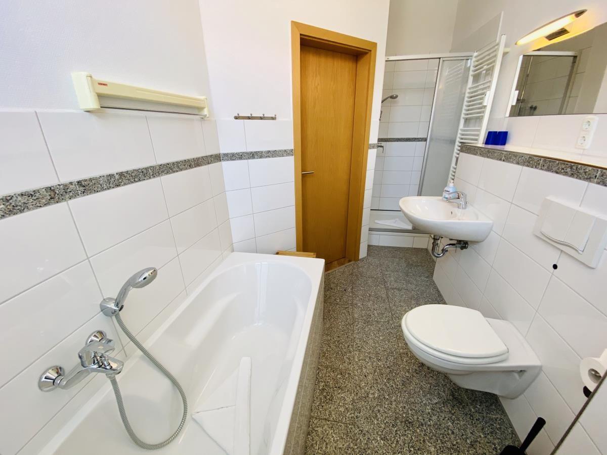 Badezimmer mit Badewanne, Dusche, Waschbecken und Toilette.