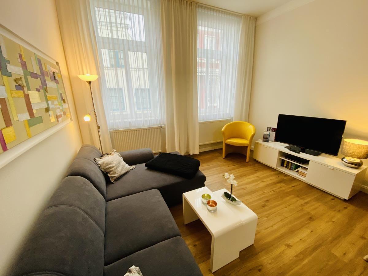 Wohnzimmer mit Sofa, Fernseher und Holzboden.