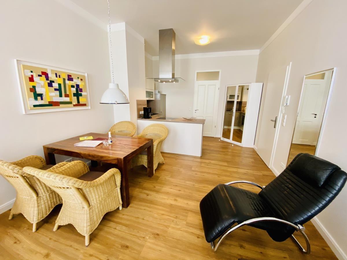 Essbereich mit Tisch und Stühlen, Küche und schwarzer Ledersessel