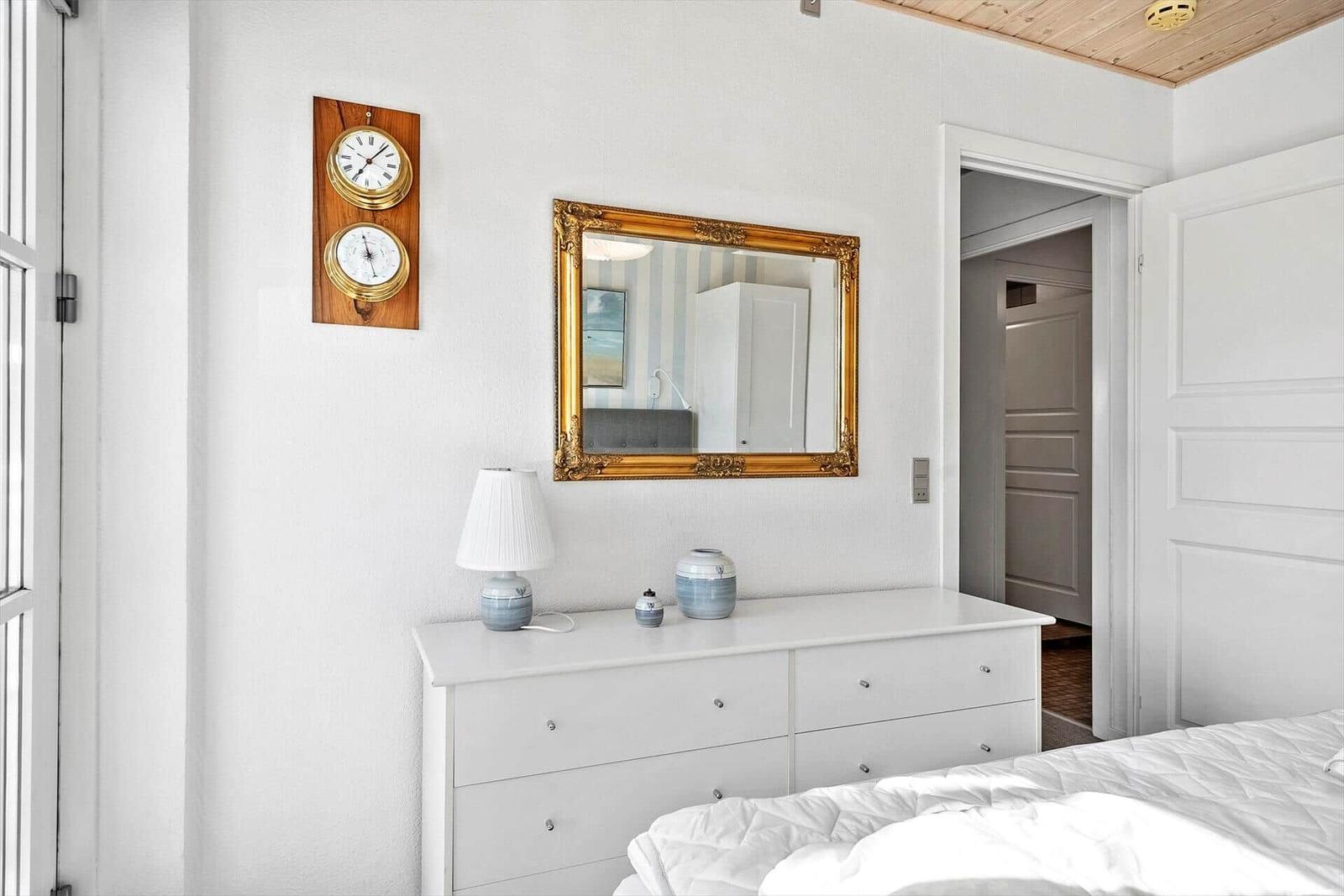 Schlafzimmer mit weißem Schrank, Spiegel und Wanduhr