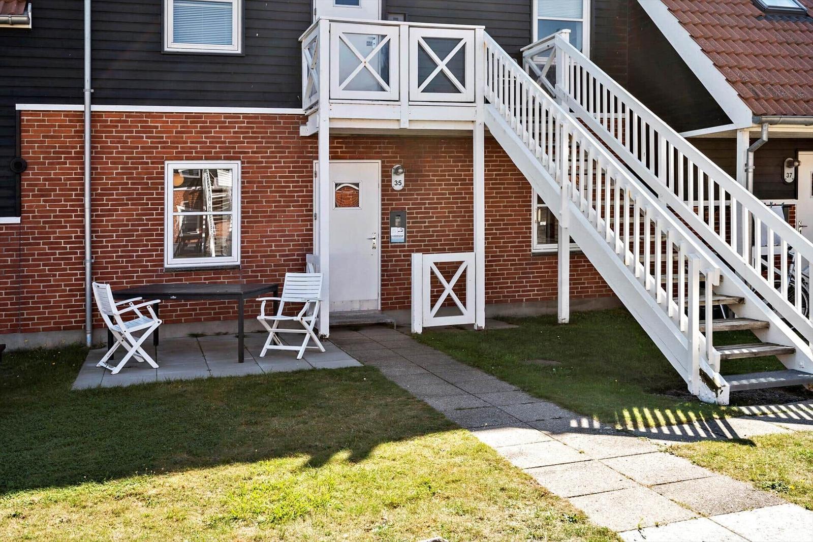 Haus mit weißer Treppe, Terrasse und Garten. Eingang mit Nummer 35.