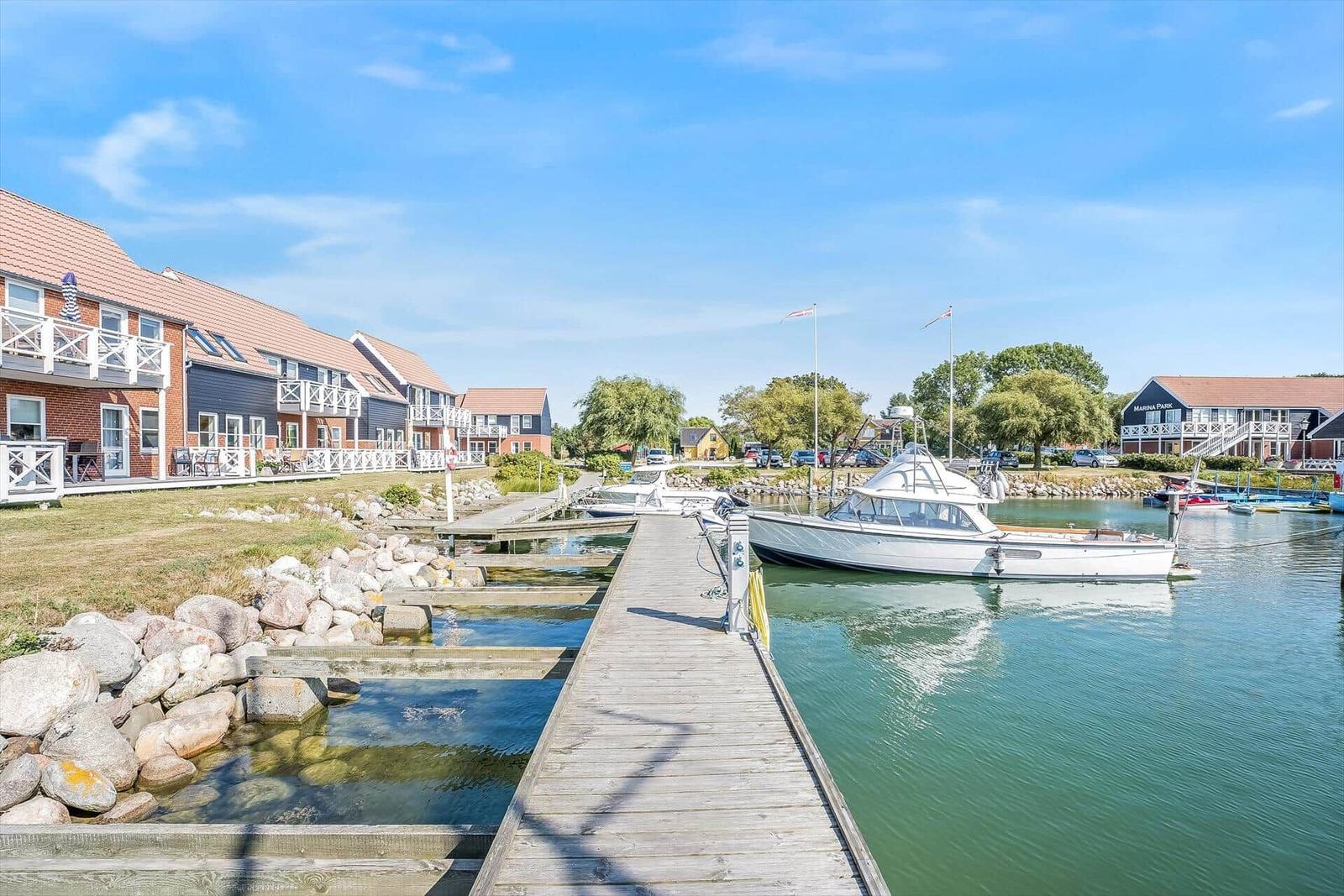 Holzsteg führt zu einem Anleger mit Booten. Hintergrund: Häuser und Marina Park.