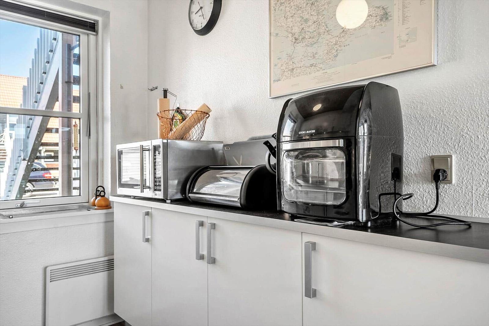 Küchenzeile mit Mikrowelle, Toaster und Kaffeemaschine neben Fenster.