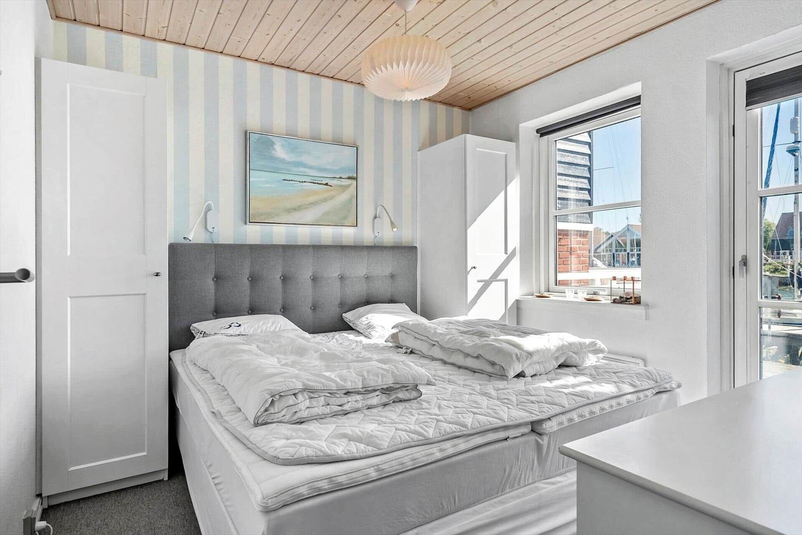 Schlafzimmer mit Bett, Fenster und Wandbild.