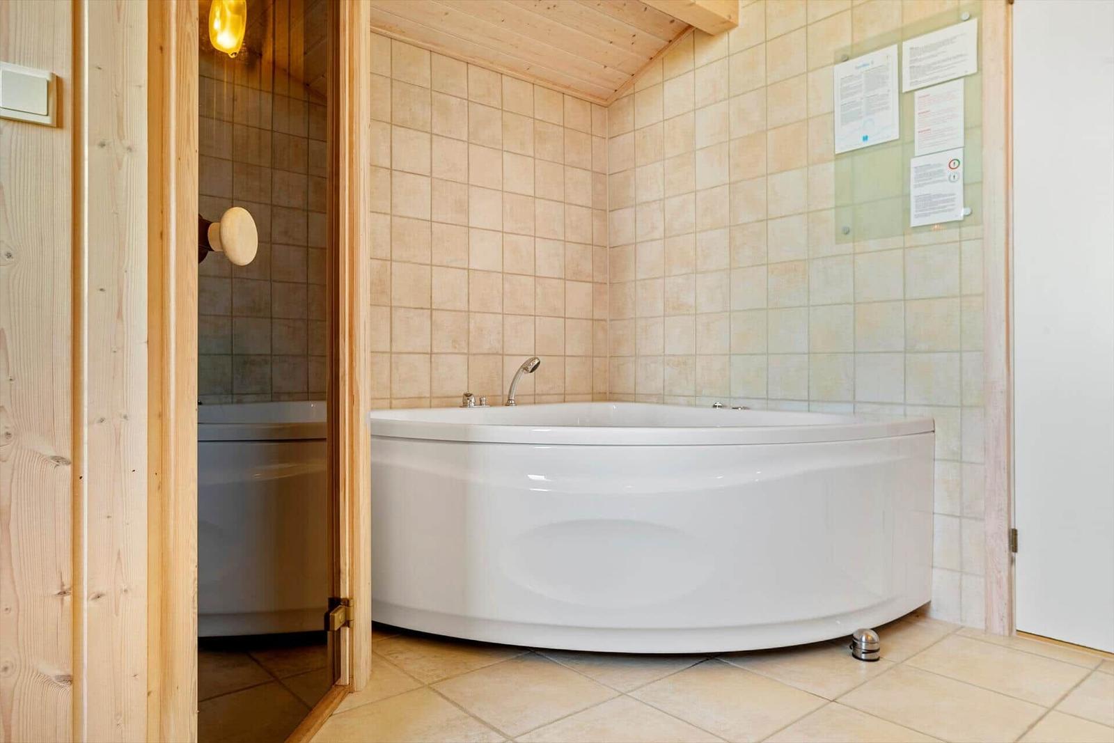 Eine große Badewanne in einem Badezimmer mit gefliesten Wänden und Holzdecke.