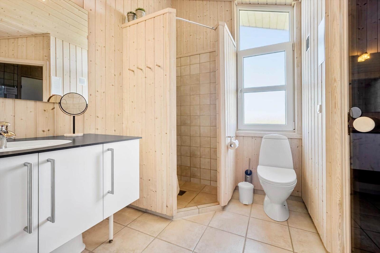 Bad mit Dusche, Toilette und Waschbecken mit Spiegel.