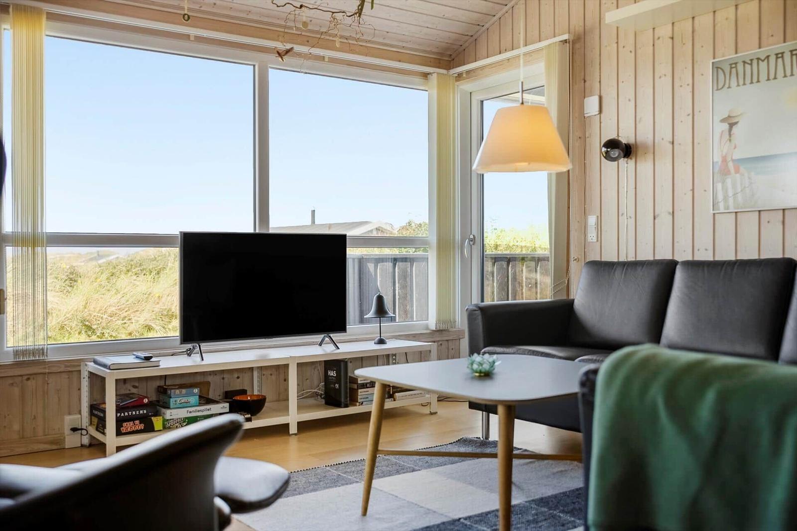 Wohnzimmer mit Sofa, TV und großem Fenster zur Aussicht.