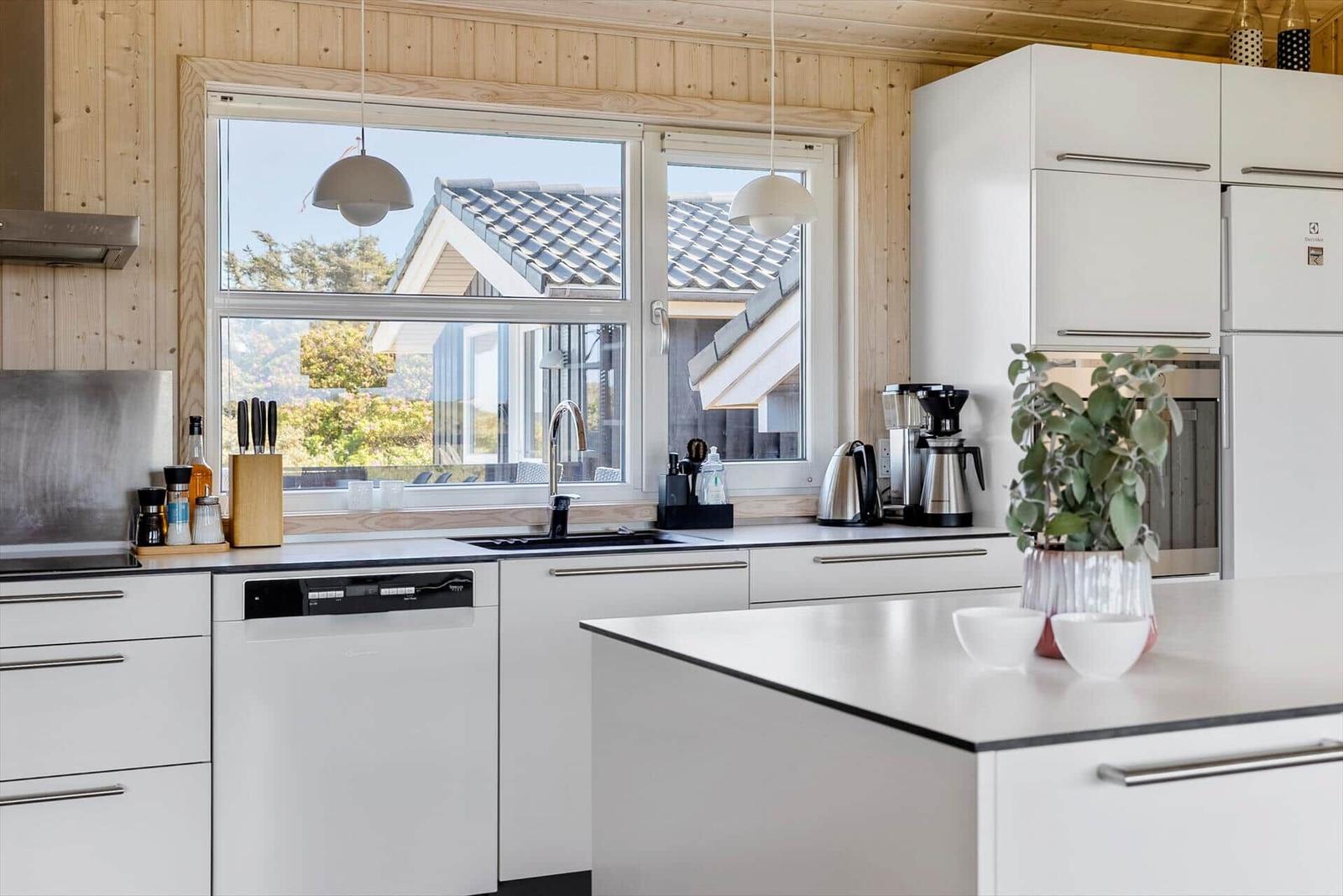 Moderne Küche mit weißen Schränken und Blick auf die Terrasse.