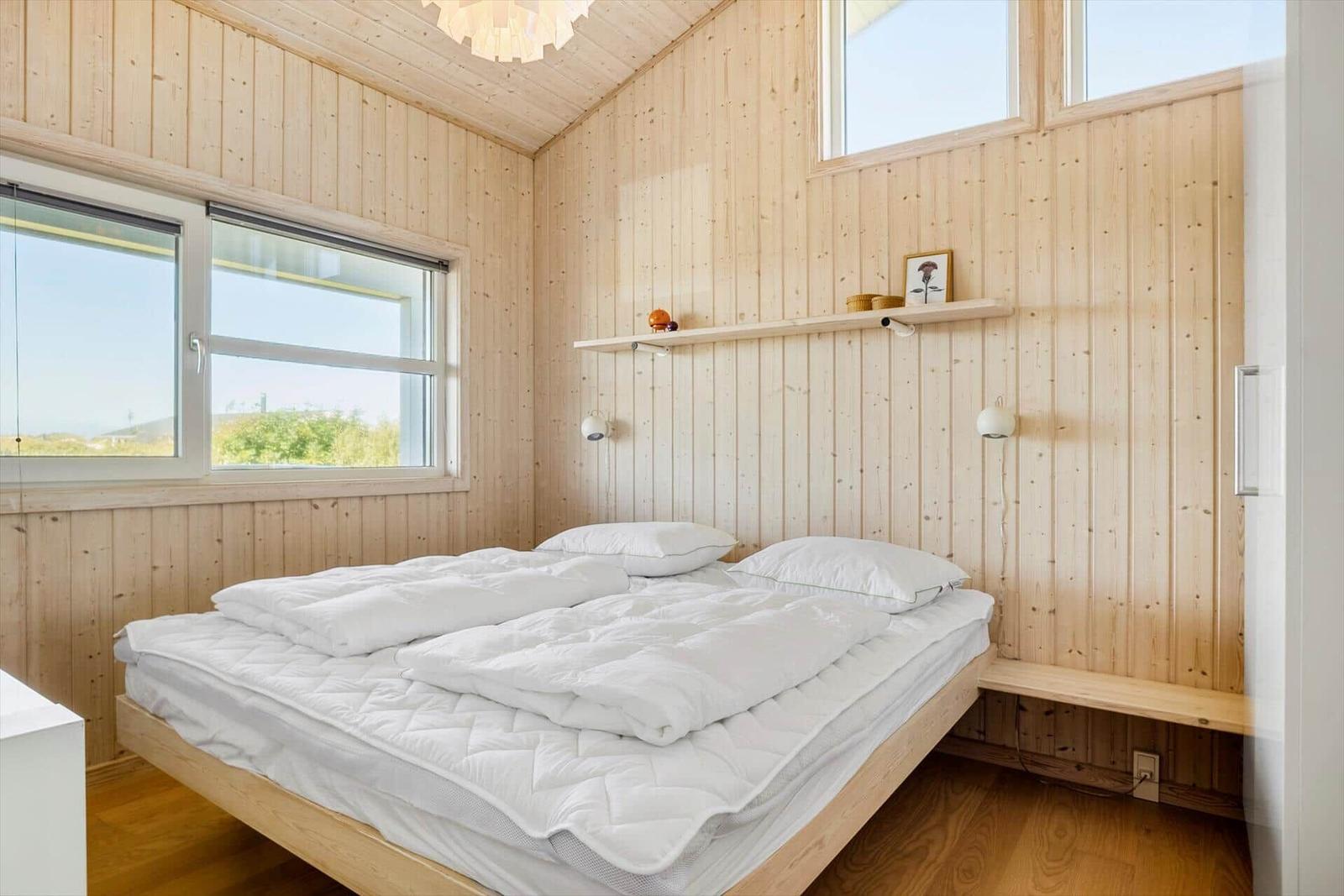 Schlafzimmer mit Holzwand, Bett und Fenster mit Blick.