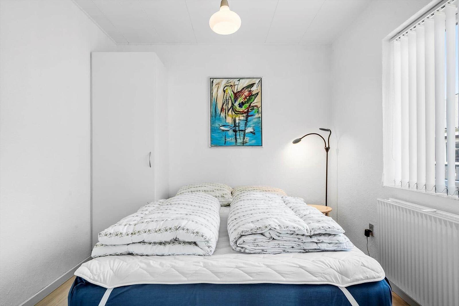 Schlafzimmer mit Bett, Kleiderschrank und Wandbild.