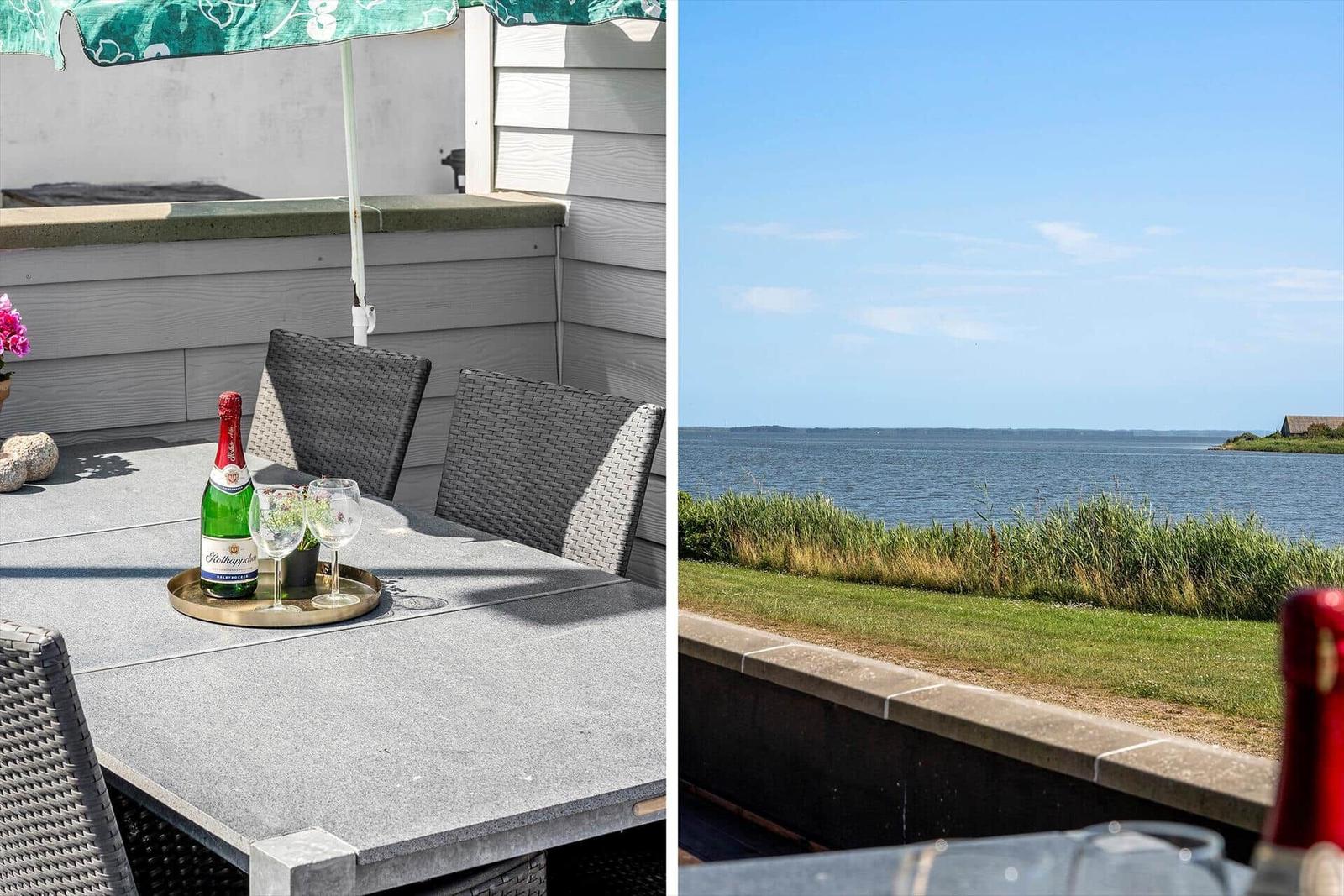 Terrasse mit Tisch, Stühlen und Blick auf Wasser