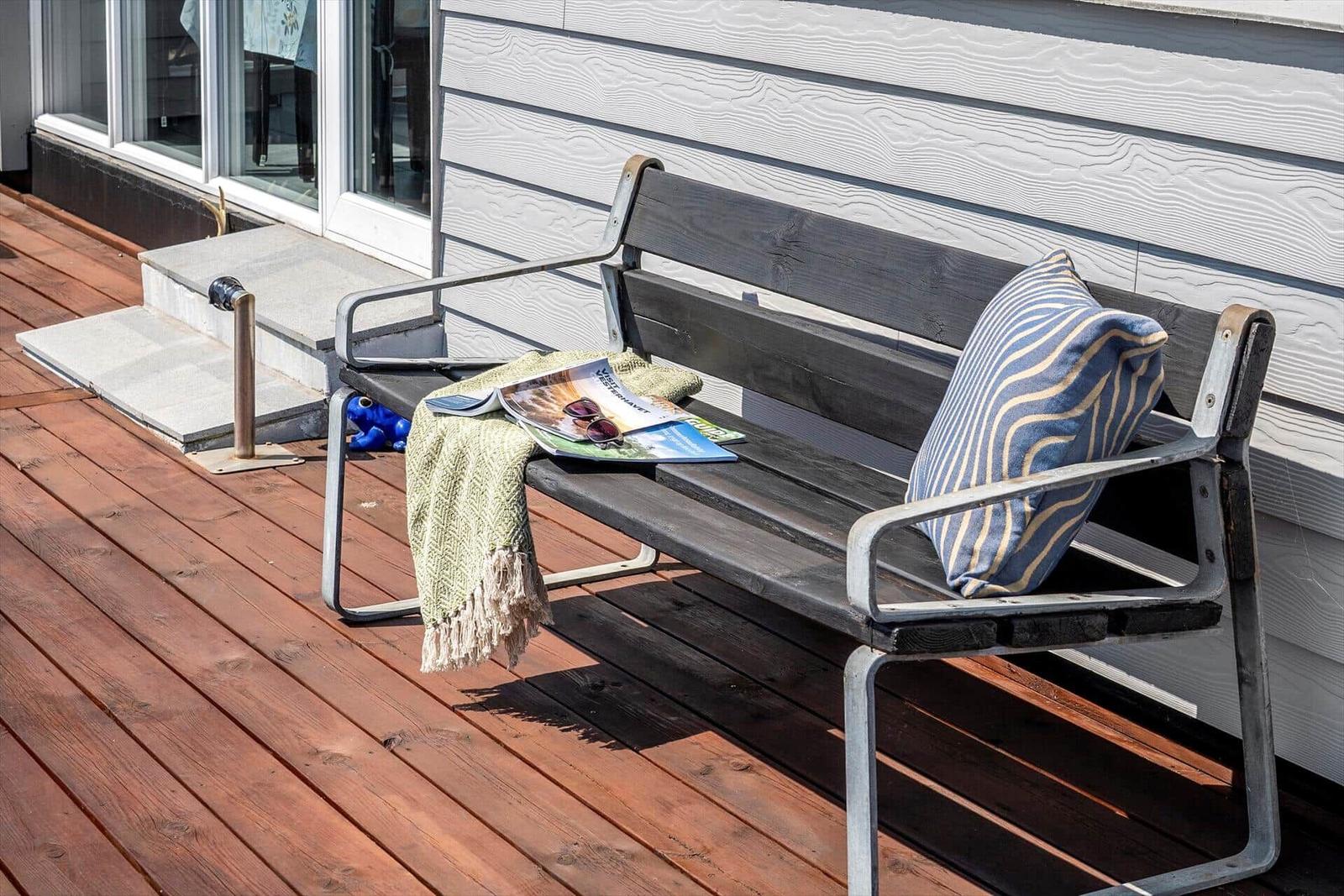 Holzterrasse mit Bank, Kissen und Zeitschrift
