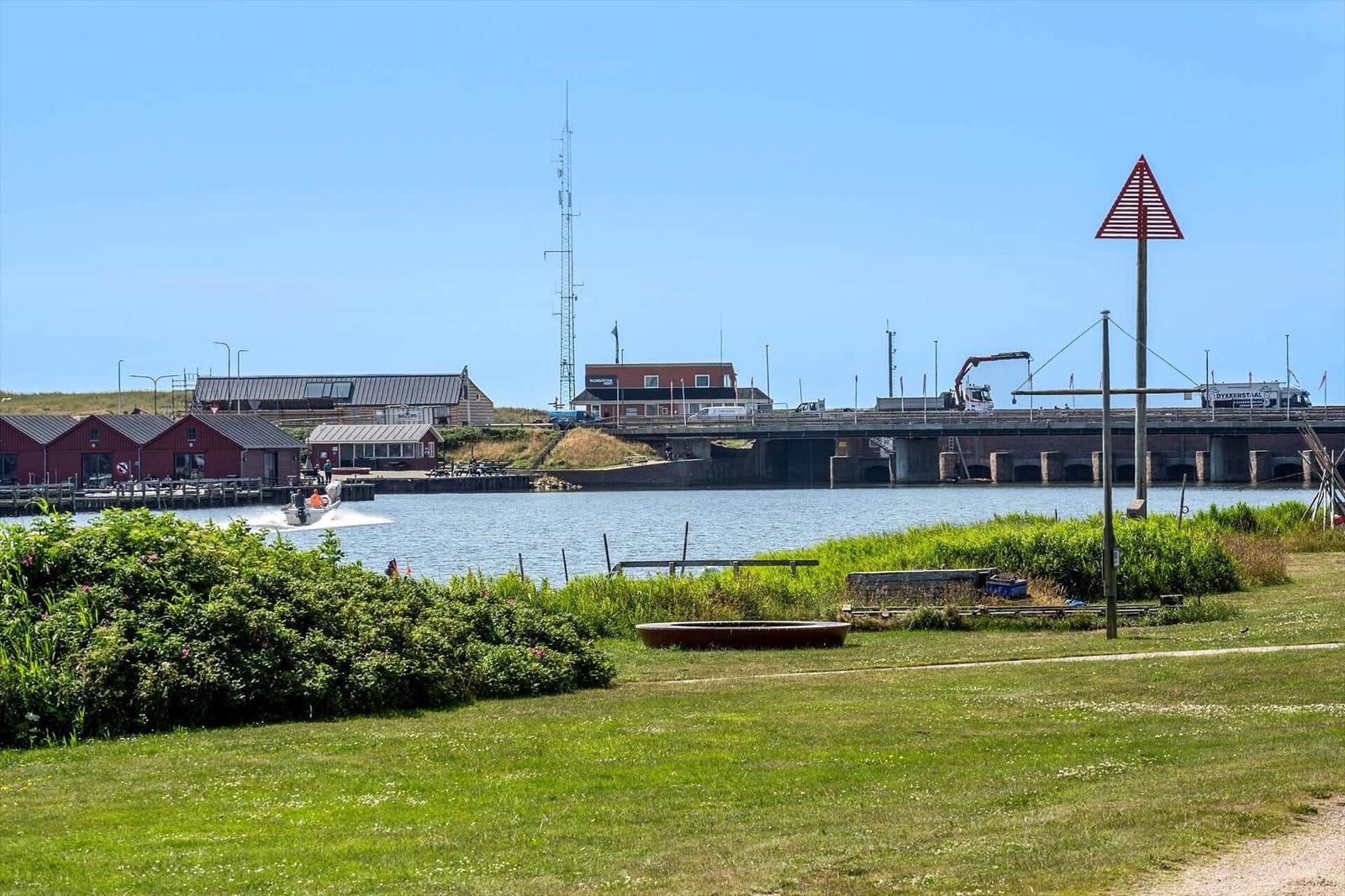 Grüner Rasenbereich mit Blick auf Wasser, Brücke und rote Gebäude.