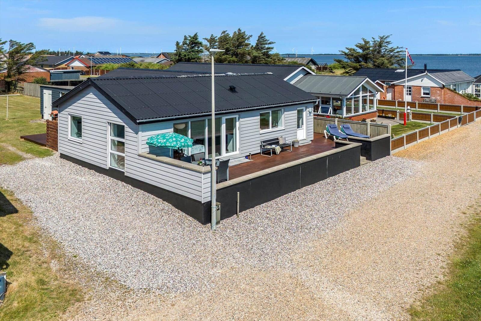 Moderne Villa mit Terrasse, Sonnenliegen und Blick aufs Wasser.