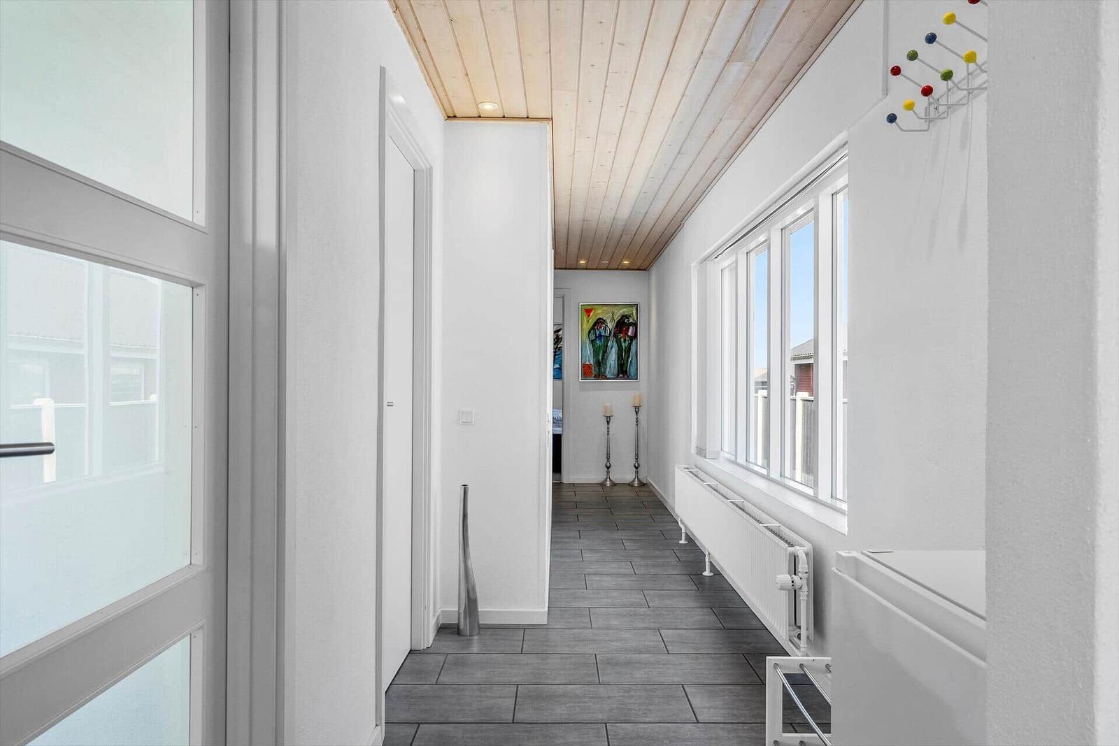 Flur mit Holzdecke, Fenstern und Wandbild.