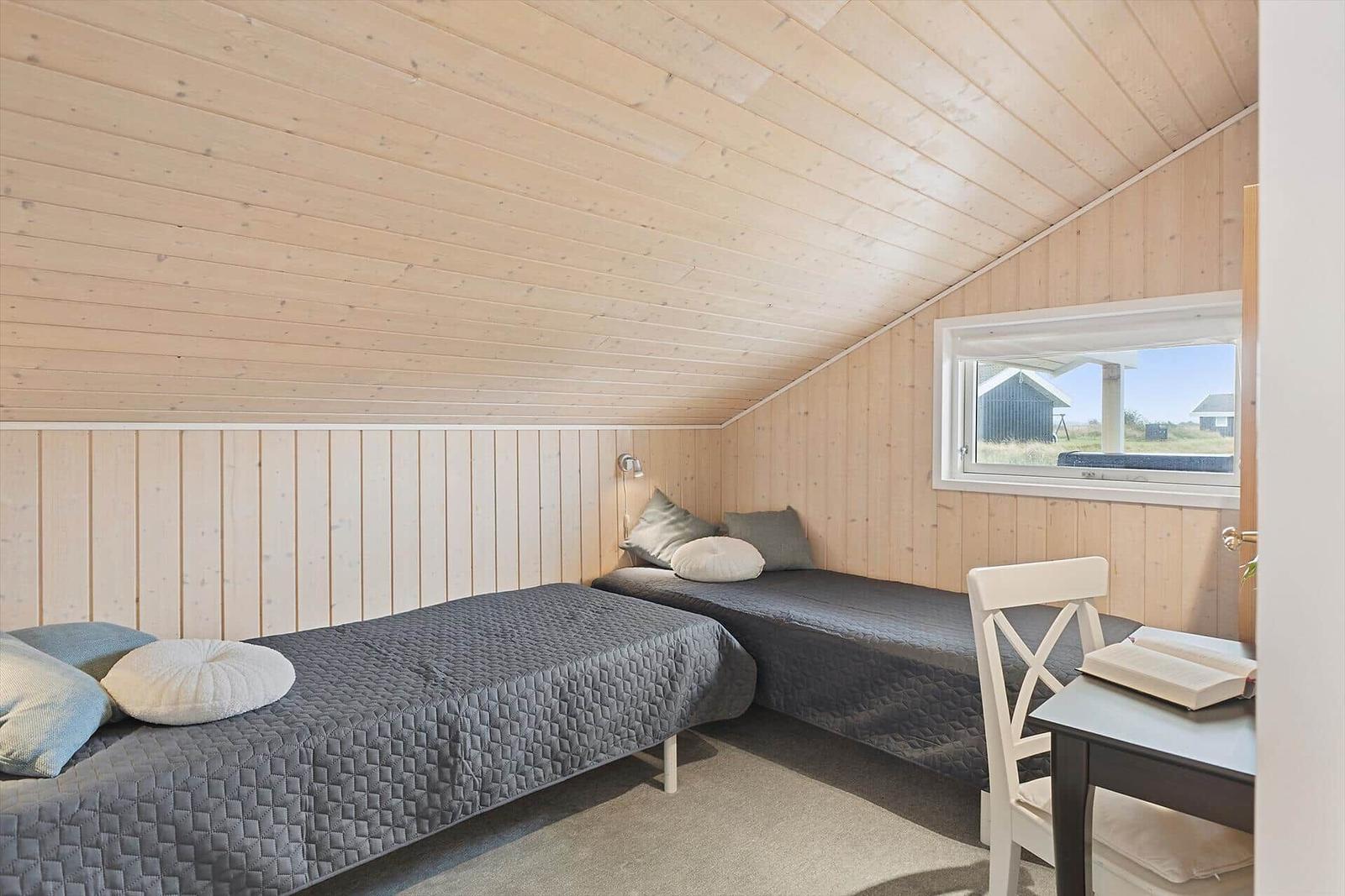 Zimmer mit zwei Betten, Holzwand und Fensterblick.