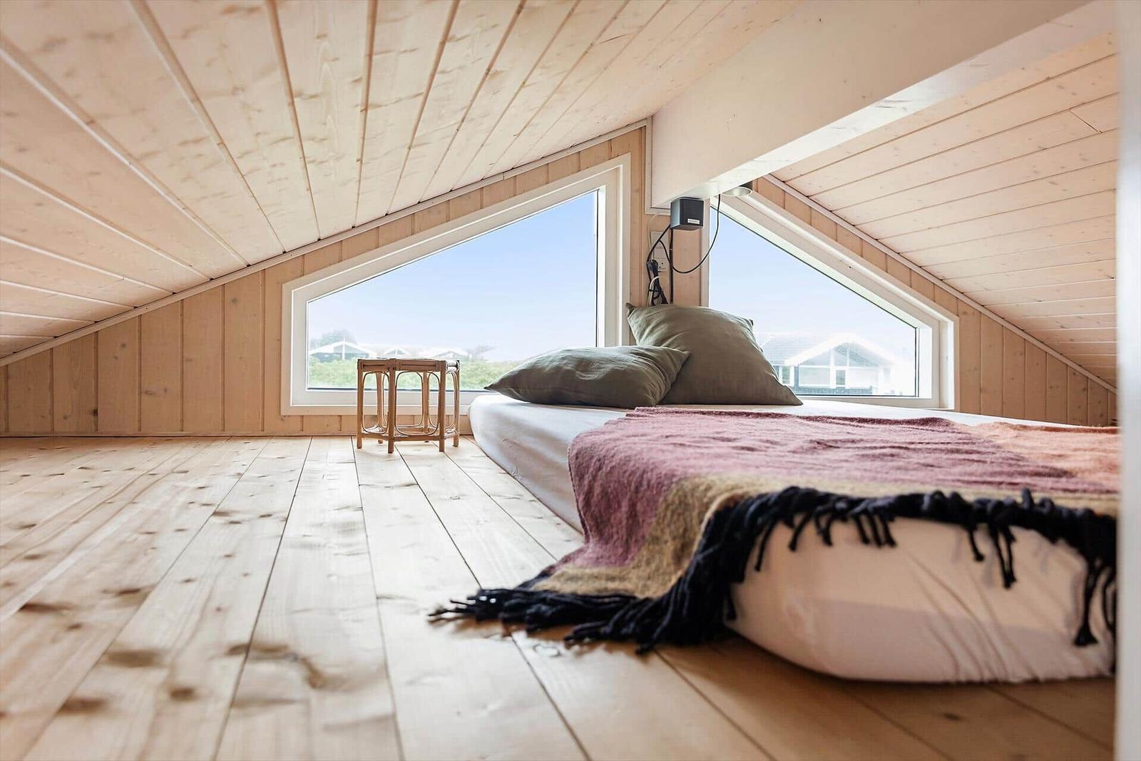 Schlafzimmer mit Bett, Fenster und Holzboden.