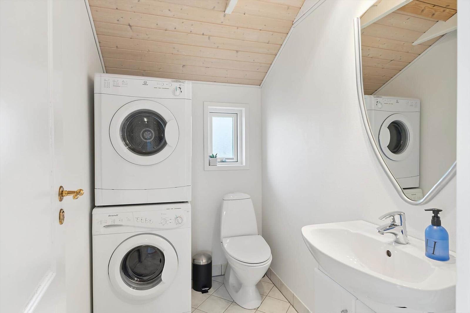 Badezimmer mit Waschmaschine, Trockner, Toilette und Waschbecken.