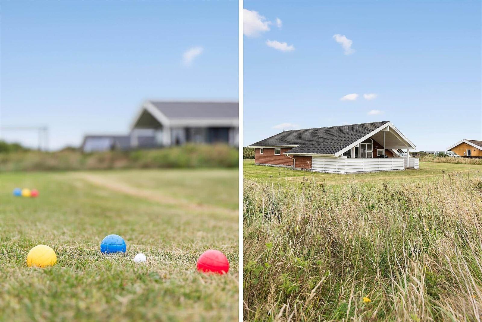 Rote, blaue und gelbe Bälle liegen auf einem Grasfeld vor einem Haus.