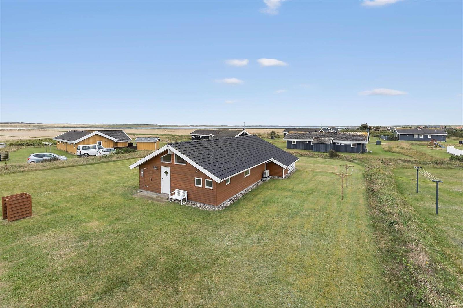 Holzhaus mit Garten, mehrere Häuser im Hintergrund, klare Himmel