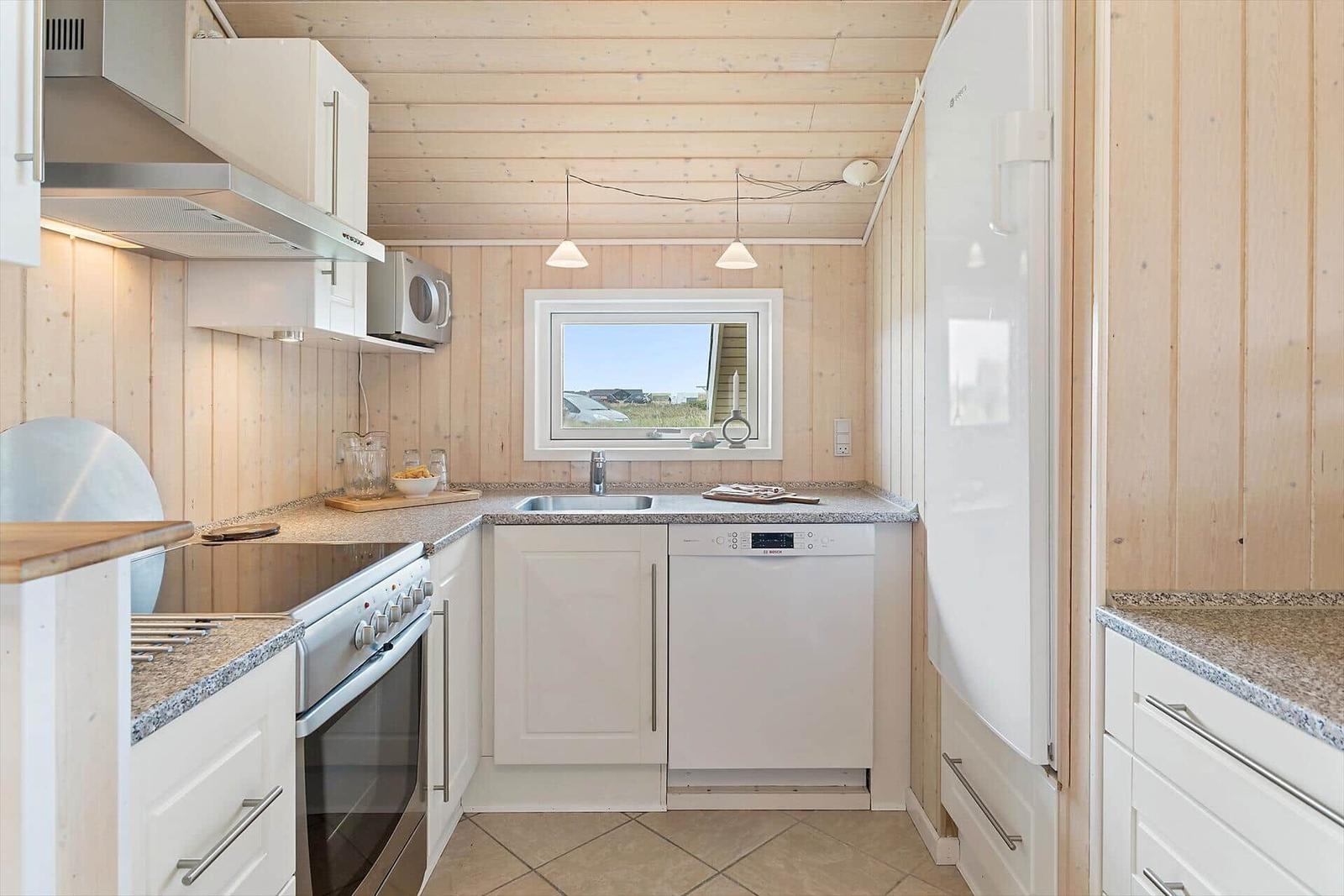 Küche mit weißen Schränken, Spüle, Herd und Kühlschrank.