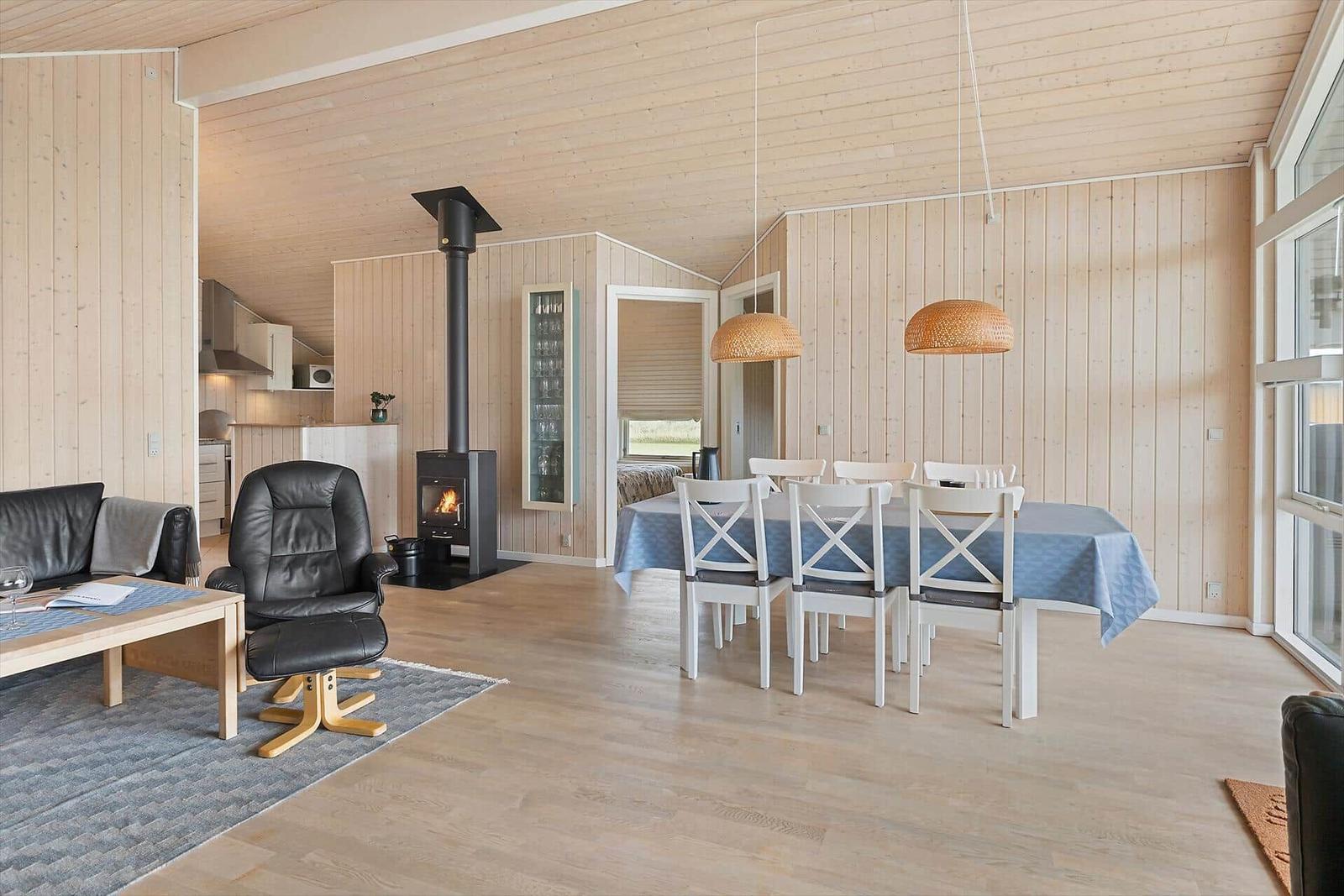 Wohn- und Essbereich mit Holzwand, Kamin und Esstisch.