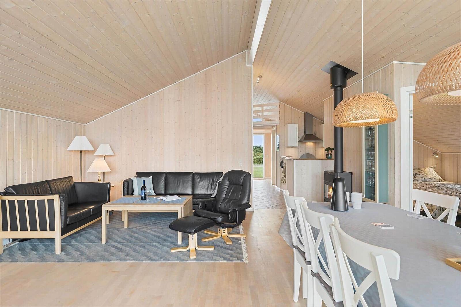 Wohn- und Essbereich mit Holzwänden, Sofa, Esstisch und Kamin.