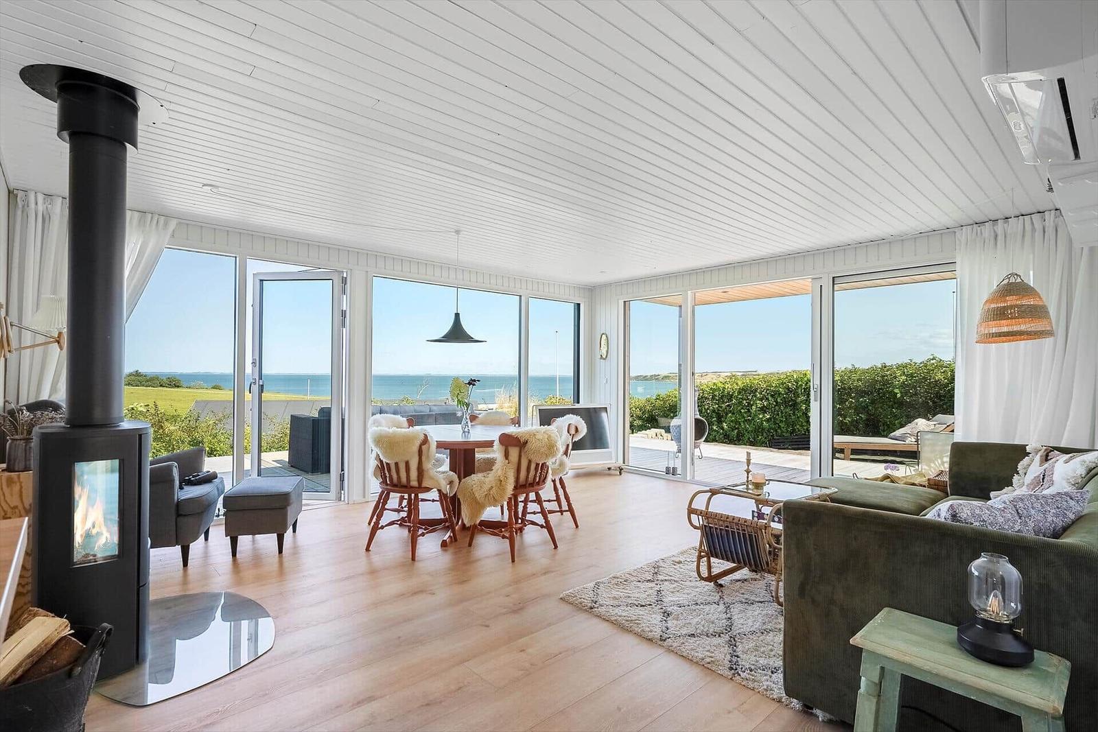 Großes Wohnzimmer mit Blick aufs Meer, Holzboden und Kamin.