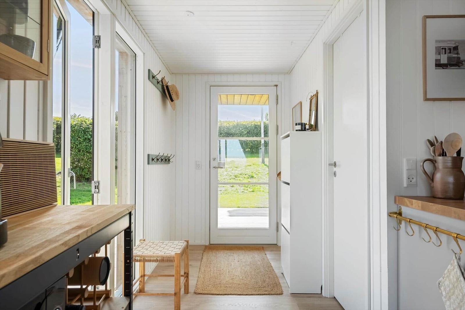 Helle Eingangshalle mit Tür zur Terrasse und Küchenbereich.