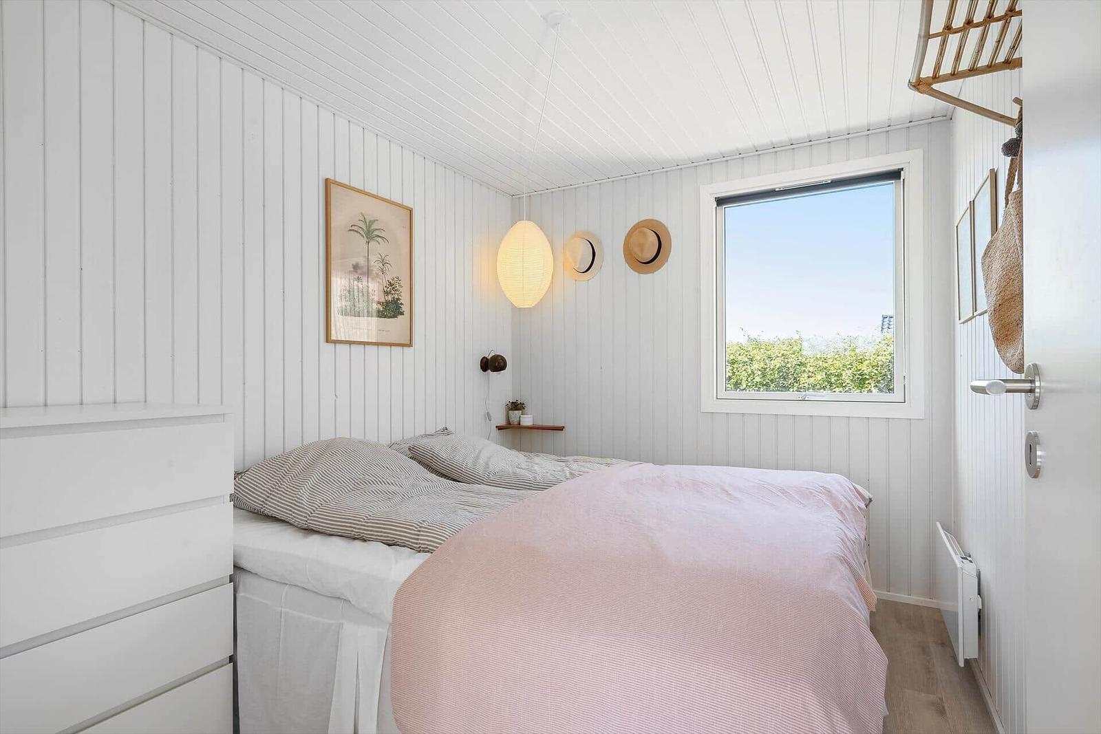 Schlafzimmer mit Bett, Fenster und Wanddekoration.