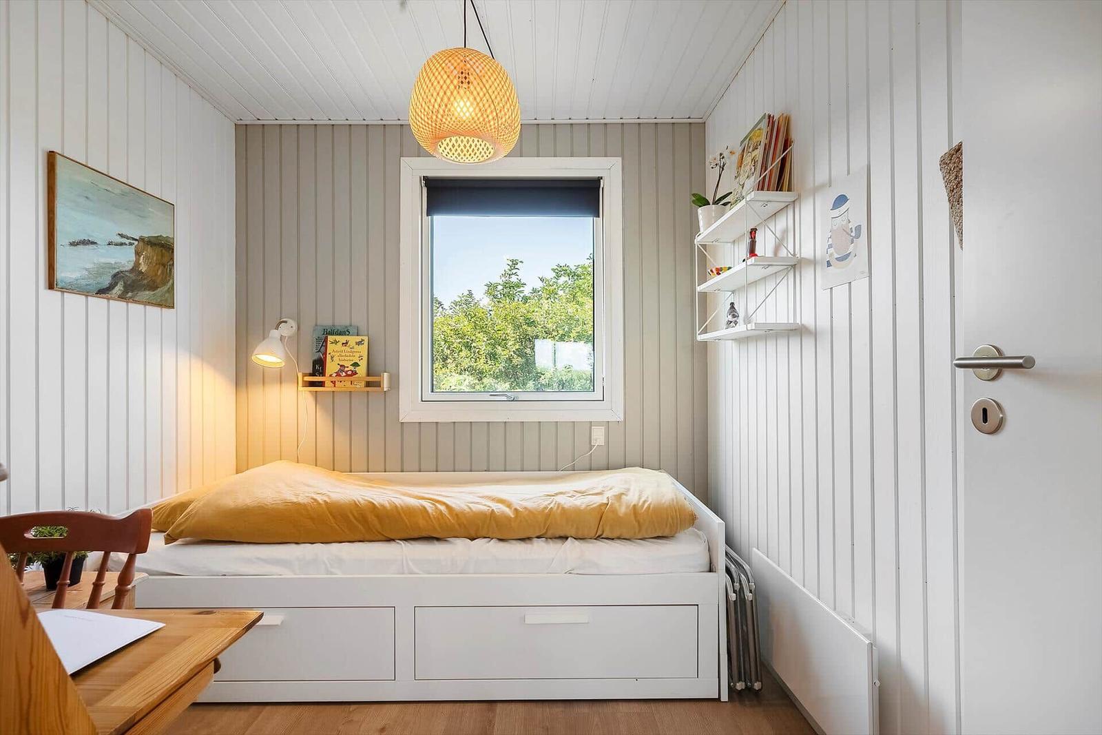 Ein Schlafzimmer mit Bett, Fenster und Wandregal.