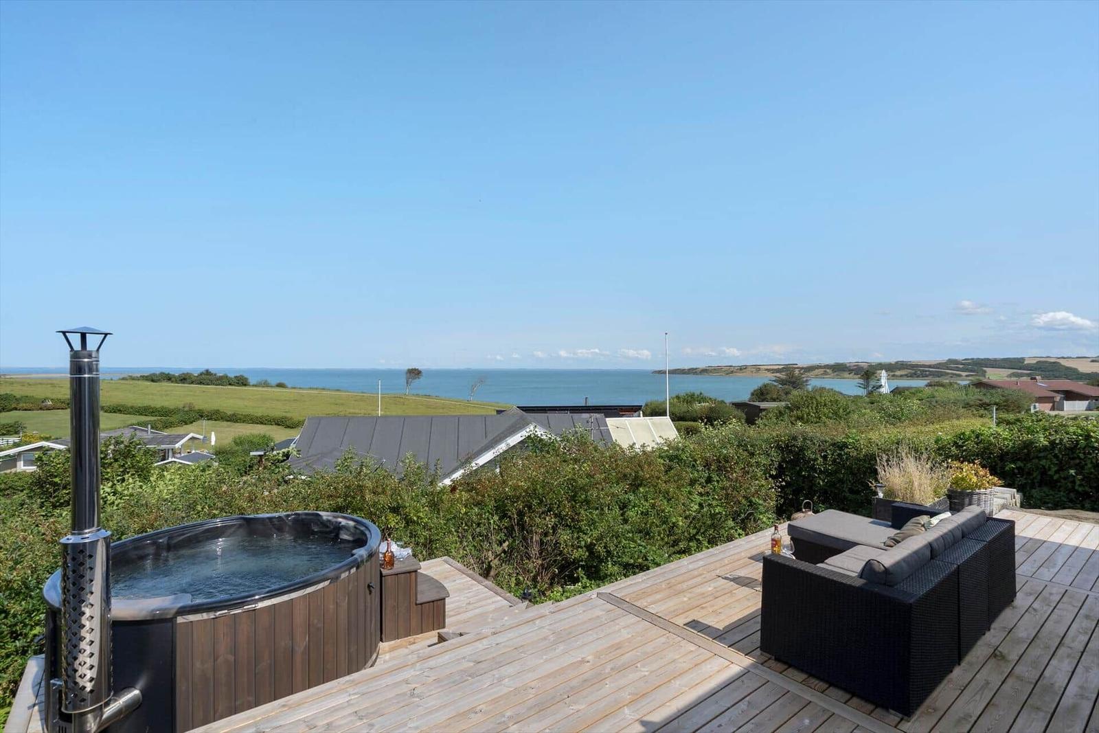 Terrasse mit Whirlpool und Sitzgruppe. Blick auf Meer und Landschaft.